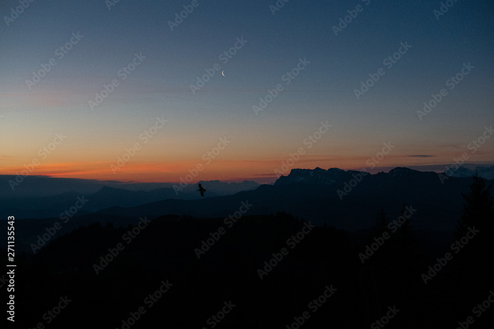 Vogel bei Sonnenaufgang mit Mond und Bergpanorma