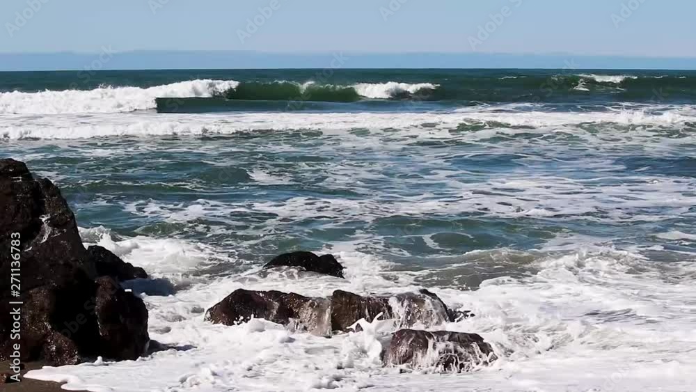 Rocks On Sandy Beach With Ocean Waves Splashing Northern California Surfer In Background Paddling Out