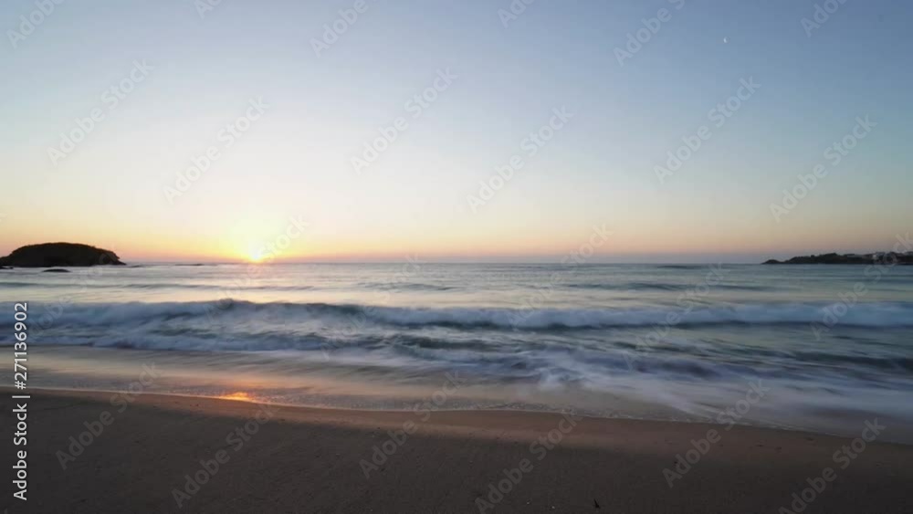 Time-lapse of a tropical beach at sunrise; silhouetted rocks in the distance. Time-lapse of a tropical beach at sunrise; silhouetted rocks in the distance.