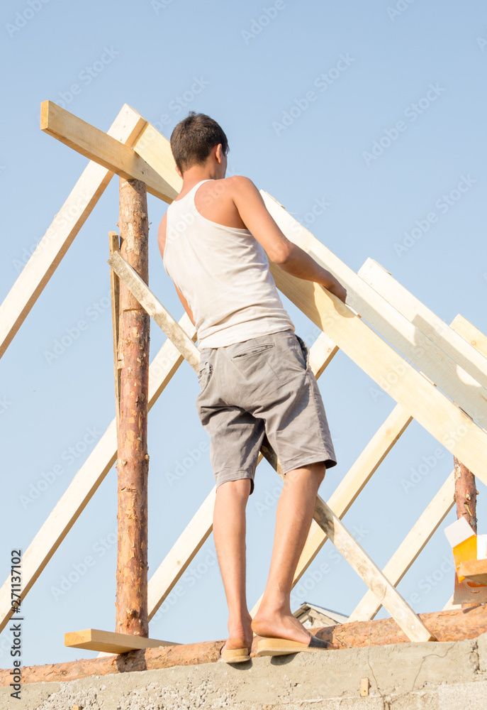 Roofer, carpenter on the roof, he closes the roof of a small and cozy house Roofer, carpenter on the roof, he closes the roof of a small and cozy house