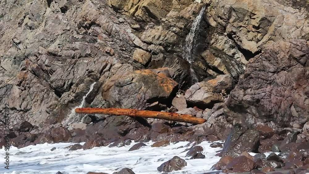 Log Sitting On Rocks At Beach With Small Waterfall Ocean Waves Log Sitting On Rocks At Beach With Small Waterfall Ocean Waves