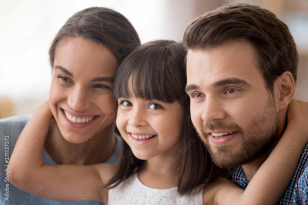 Funny little girl posing for picture hugging young parents