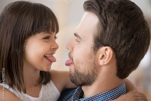 Playful dad and daughter play game showing tongues