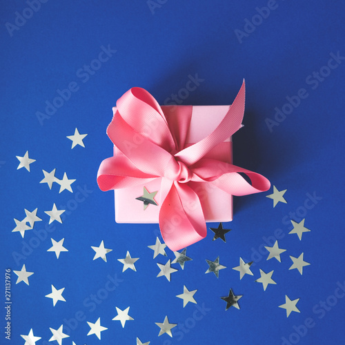 Fototapeta Naklejka Na Ścianę i Meble -  Pink gift box with a pink ribbon on a blue background .