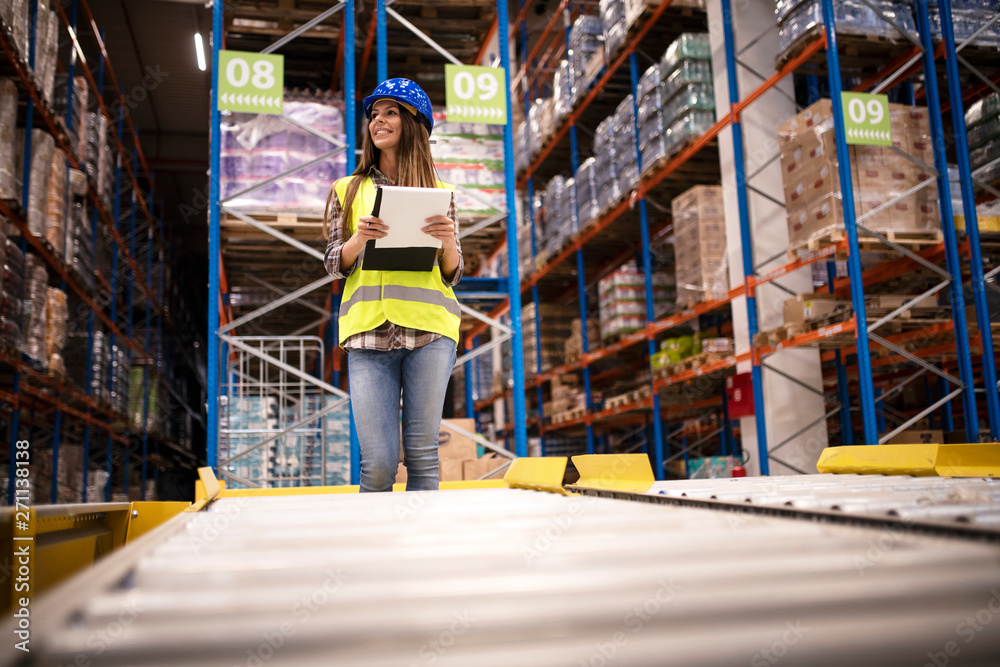 Beautiful woman worker with hardhat and checklist controlling distribution in warehouse center. Beautiful woman worker with hardhat and checklist controlling distribution in warehouse center.