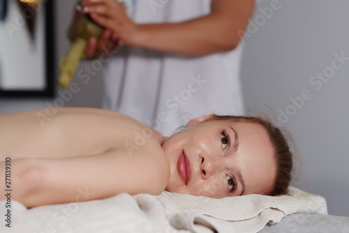 Blond European girl is having relaxing massage procedure in a spa salon.