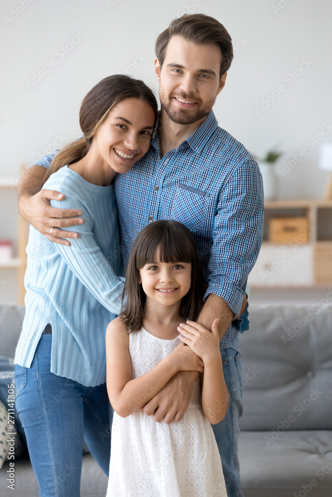 Family portrait of loving parents hug posing with little daughter Family portrait of loving parents hug posing with little daughter