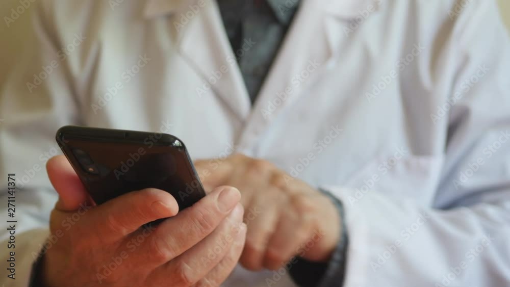 Elderly Doctor Using A Phone In His Hands. Elderly Doctor Using A Phone In His Hands.