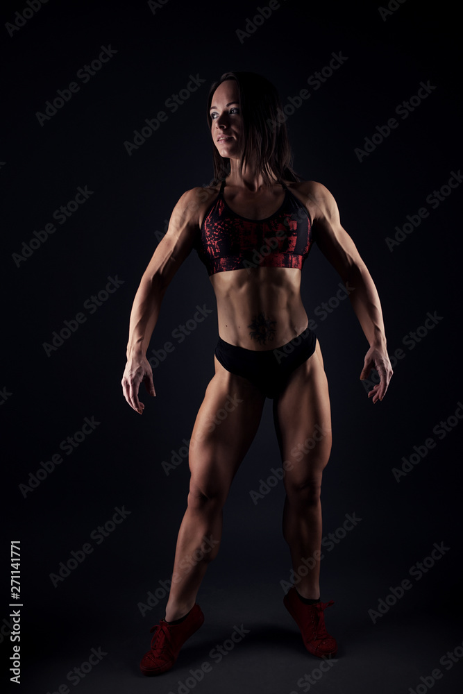 Image of fitness woman in sports clothing looking down. Young female model with muscular body.
