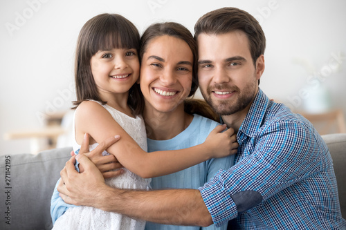 Portrait of happy family with kid hugging posing for picture