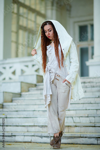 dreadlocks fashionable girl dressed in white posing on old palace background