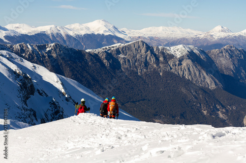 3 mountain climbers walk on snow in the mountains