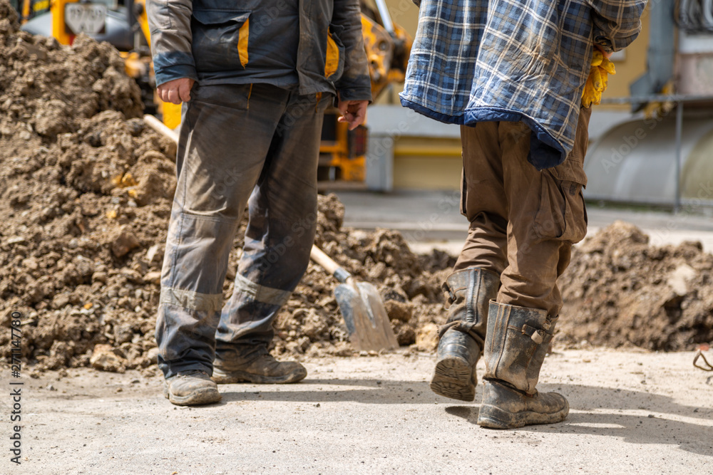 A group of workers stand near an open pit in dirty clothing. A group of workers stand near an open pit in dirty clothing.
