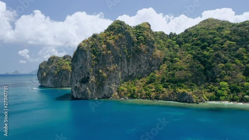 Limestone rocks of Lagen island. El Nido, Palawan, Philippines. Paradise tropical sandy Ipil Beach with azure turquoise sea water, coconut palm trees and local banca boats moored. photo