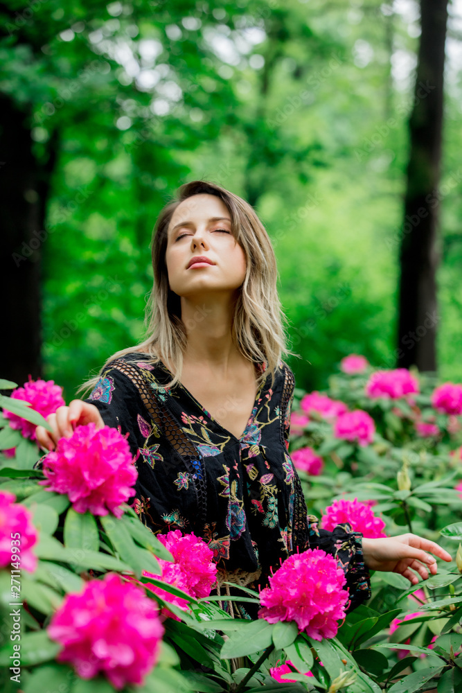style woman near rhododendron flowers in a grarden in spring time