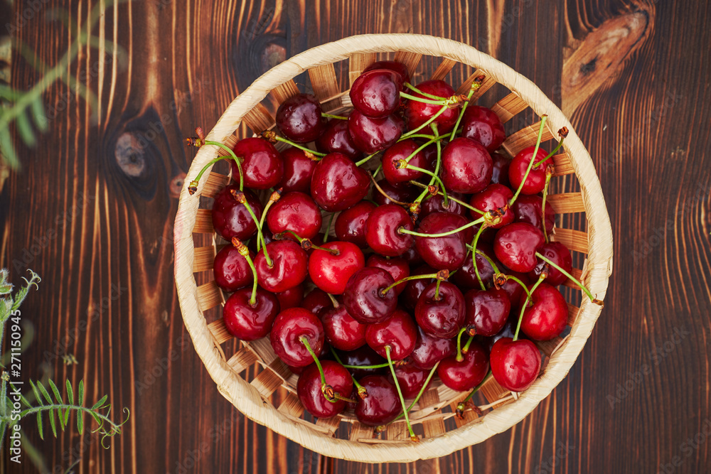 cherries in bowl and near on wooden background