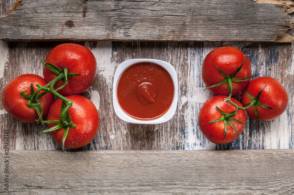 Food banner tomatoes on a branch and ketchup or tomato sauce on a rustic background. Horizontal wood frame Food banner tomatoes on a branch and ketchup or tomato sauce on a rustic background. Horizontal wood frame