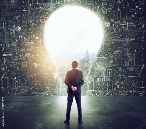 Photography Businessman looks at a big hole on the wall shaped as a light bulb
