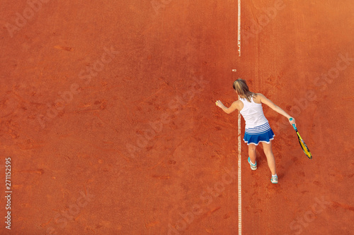 Aerial shot of a female tennis player on a court during match. Young woman playing tennis.High angle view. © FS-Stock