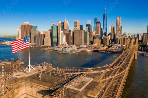 American flag on top of the Brooklyn bridge with Manhattan view on the background.