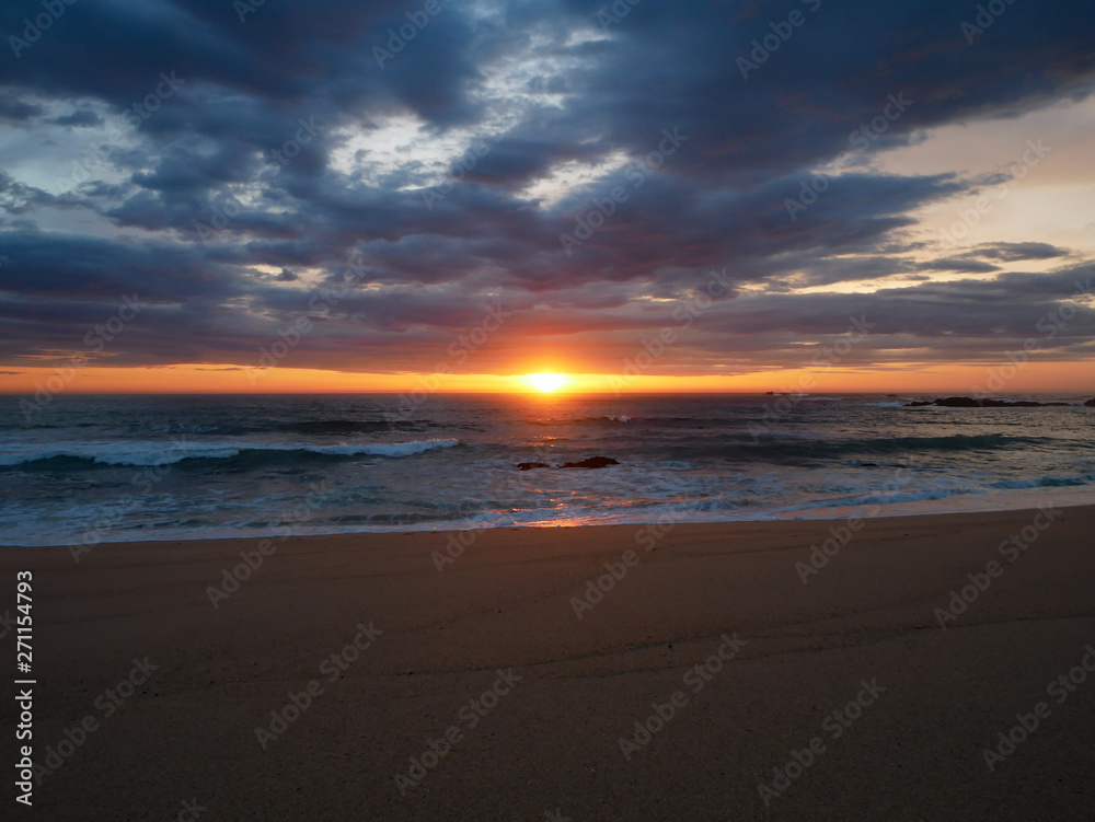 Empty beach at sunset with vivid sky and dramatic clouds