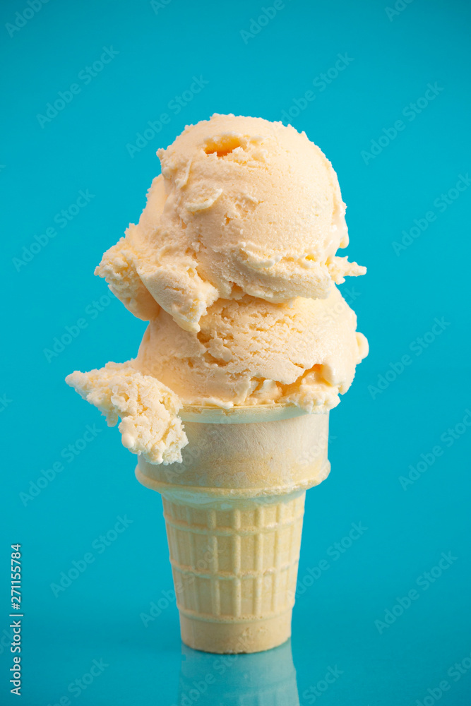 A Double Scoop Vanilla Ice Cream Cone on a Blue Background Stock Photo