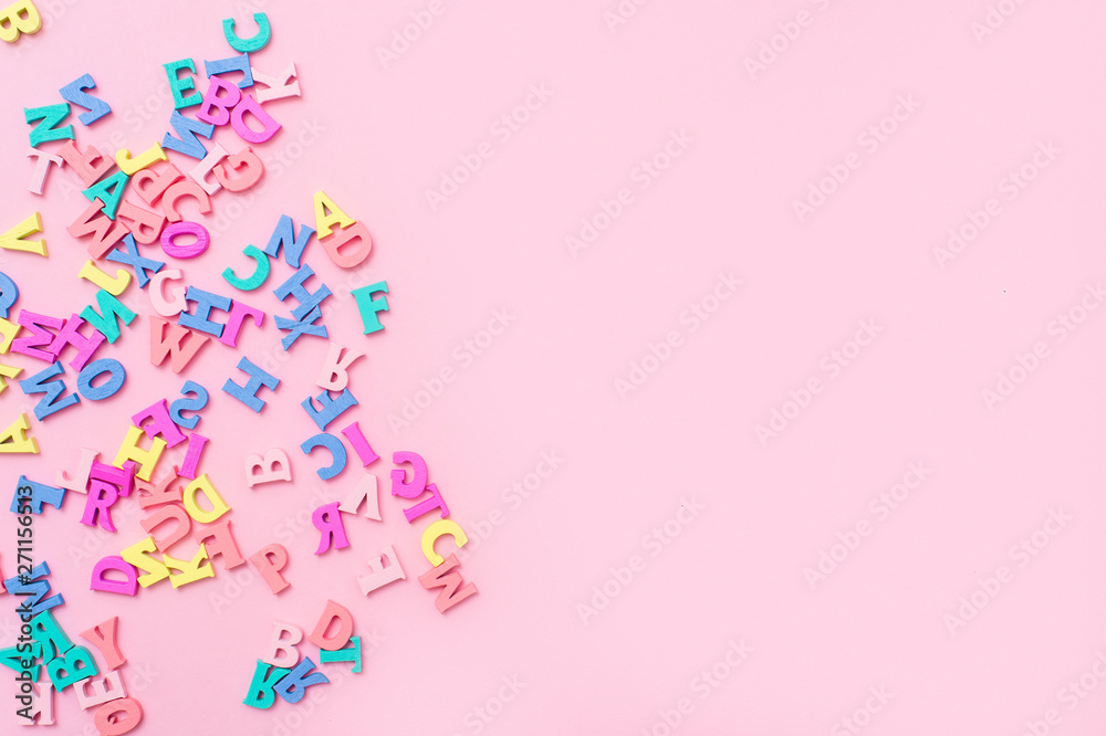 Many multicolored wooden letters on a pink background. toy letters. english alphabet. View from above. Flat lay. Copy space for text
