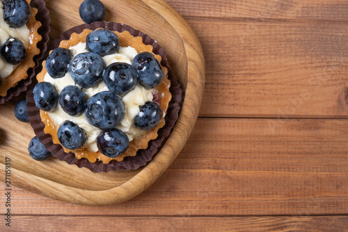 bilberry tartlet on a wooden plate on the table, bilberry baked shell, fruit cupcake with blueberry