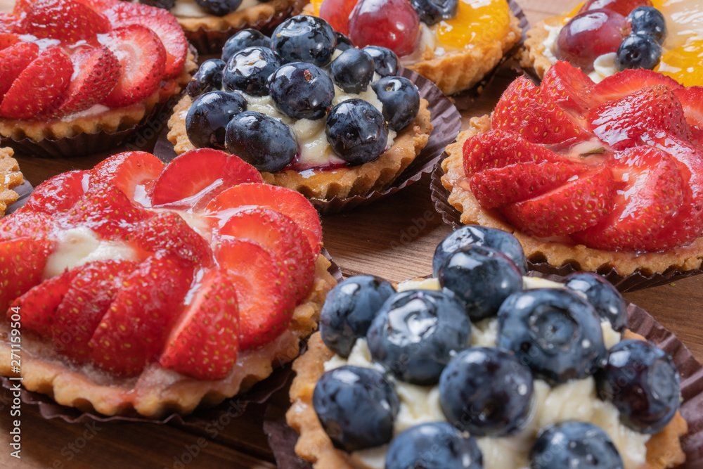 fruit tartlets on a wooden plate on the table, fruit baked shell, fruit cupcake with berry