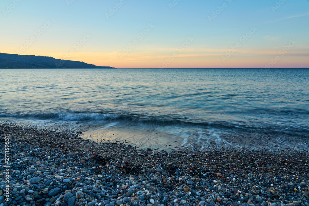 The sunset on the pebble beach with hills on the background, Kolymbari, Crete, Greece. The sunset on the pebble beach with hills on the background, Kolymbari, Crete, Greece.