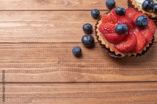 fruit tartlets on a wooden plate on the table, fruit baked shell, fruit cupcake with berry