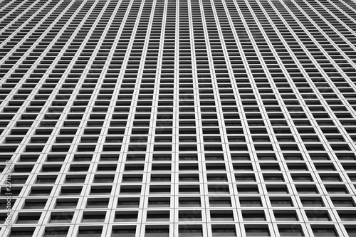 Black and white image of the outgoing perspective of the windows of the facade of a modern building. Glass grey square Windows of modern city business building skyscrape. Texture.