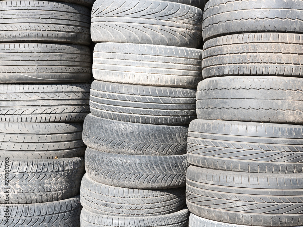 Used, old tires stacked one on another next to shop garage. Used, old tires stacked one on another next to shop garage.