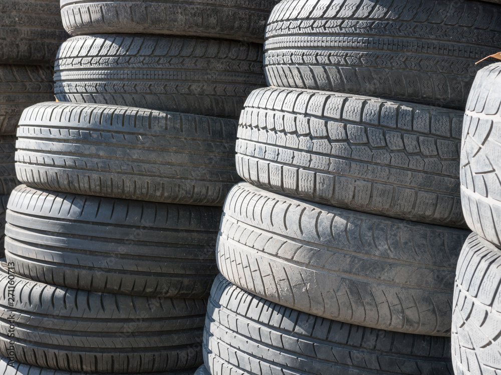 Used, old tires stacked one on another next to shop garage. Used, old tires stacked one on another next to shop garage.
