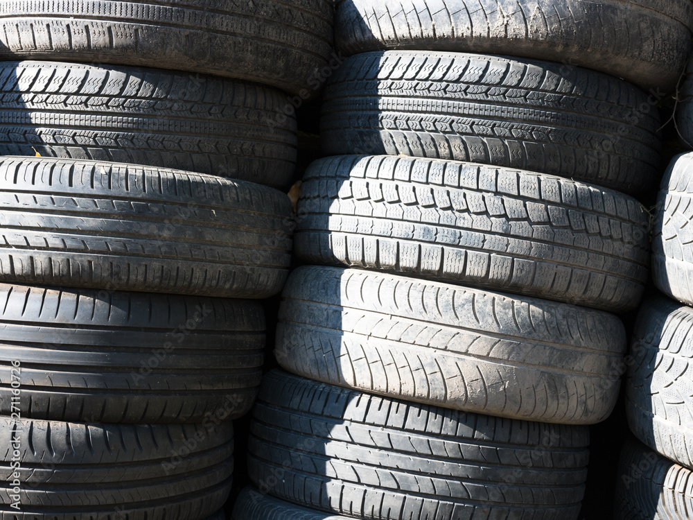 Used, old tires stacked one on another next to shop garage. Used, old tires stacked one on another next to shop garage.
