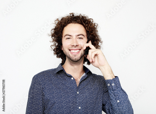 Smiling young man  talking by smartphone and looking at the camera