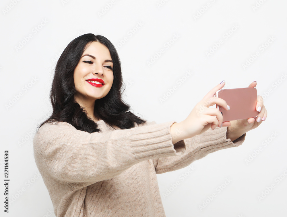 Fashion curvy brunette girl taking photo makes self portrait on smartphone Fashion curvy brunette girl taking photo makes self portrait on smartphone