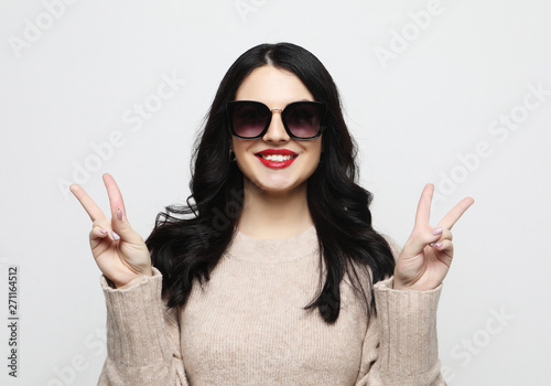  woman looking at camera with smile and showing peace sign with fingers