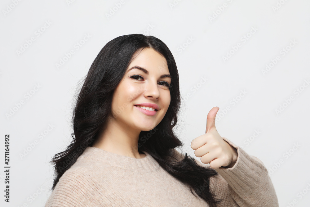 Happy young caucasian female making thumb up sign and smiling cheerfully, showing her support and respect to someone. Happy young caucasian female making thumb up sign and smiling cheerfully, showing her support and respect to someone.