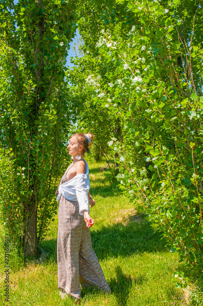 Beautiful boho style woman in fashionable jumpsuit enjoying summer time in park Beautiful boho style woman in fashionable jumpsuit enjoying summer time in park