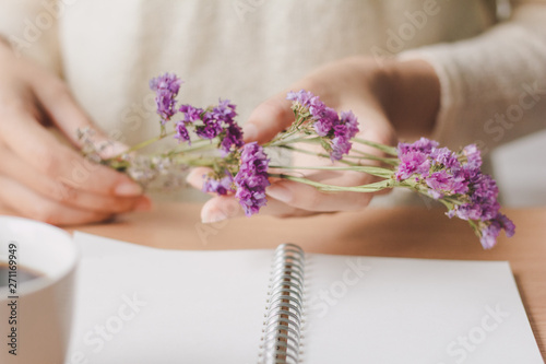 Woman hand holding purple dry flower on desk office.