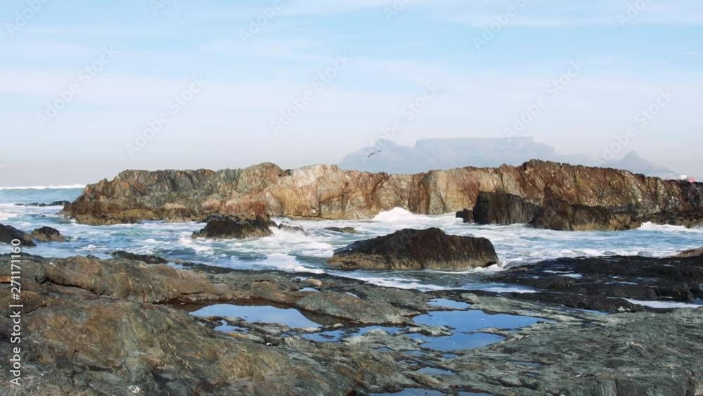 Table Mountain from behind a cluster of granite rocks on the edge of Table Bay on a beautiful morning. Table Mountain from behind a cluster of granite rocks on the edge of Table Bay on a beautiful morning.