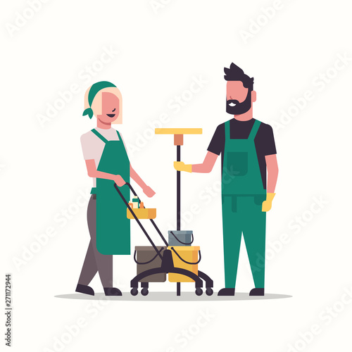 couple janitors man woman in uniform working together with professional equipment cleaning service concept cleaners pushing trolley cart with tools full length flat