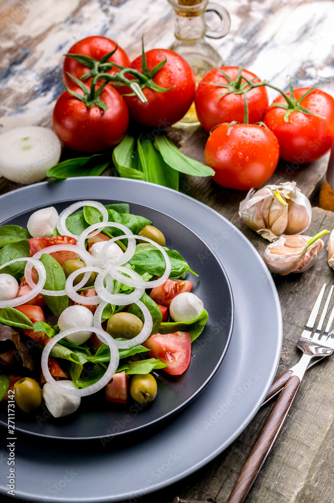 Close Up healthy and tasty salad from fresh herbs with mozzarella, tomatoes, olives and onions. Mediterranean traditional cuisine.