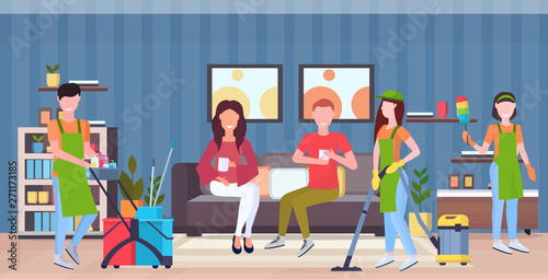 janitors team cleaners in uniform working together with professional equipment cleaning service concept couple sitting on couch modern living room interior flat full length horizontal
