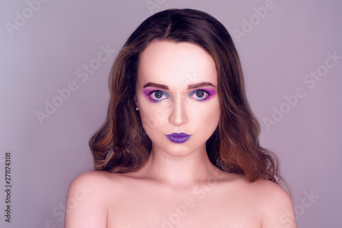 Fashion model with creative pink and blue make up. Beauty art portrait of beautiful girl with colorful abstract makeup. Beautiful Eyes Glitter . Purple bright lips, long cerly hair. Gray background