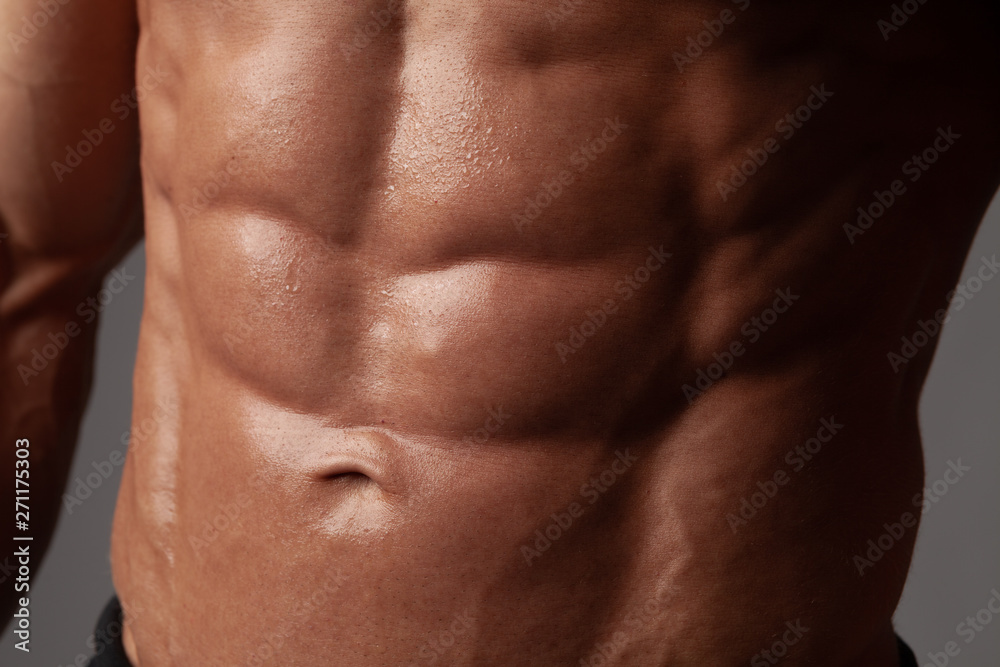 Male abdominal muscles closeup with sweat drops after exercise