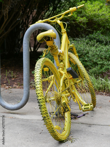 Painted Yellow bicycle locked to bike rack in urban setting