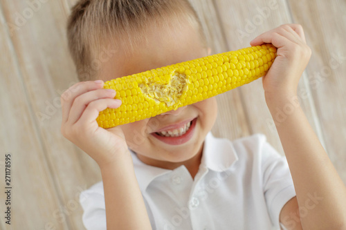 Obraz na płótnie The child eats delicious corn at home