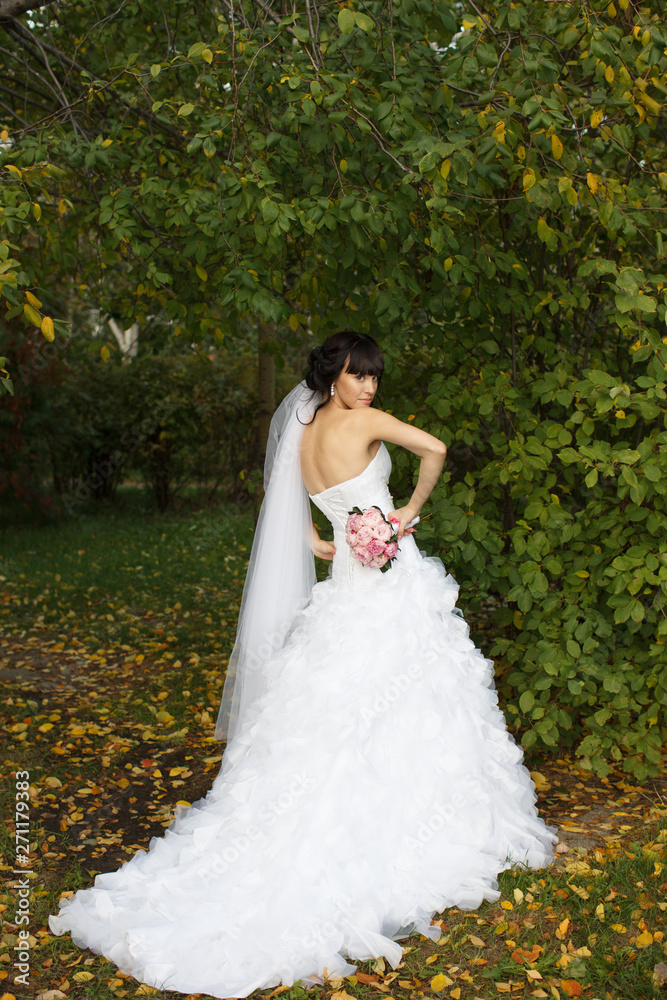 Beauty portrait of bride wearing fashion wedding dress with feathers with luxury delight make-up and hairstyle, studio indoor photo. 